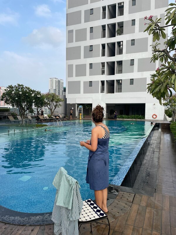 "Sophia steht in ein Handtuch gewickelt vor einem Pool mit blauem Wasser."