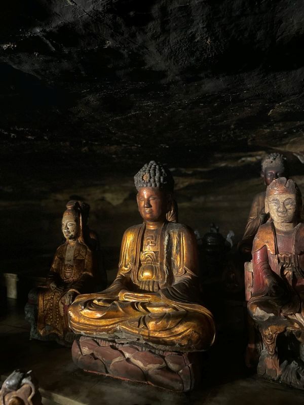 "Eine Buddhastatue und einige Holzfiguren in einer der Höhlen."