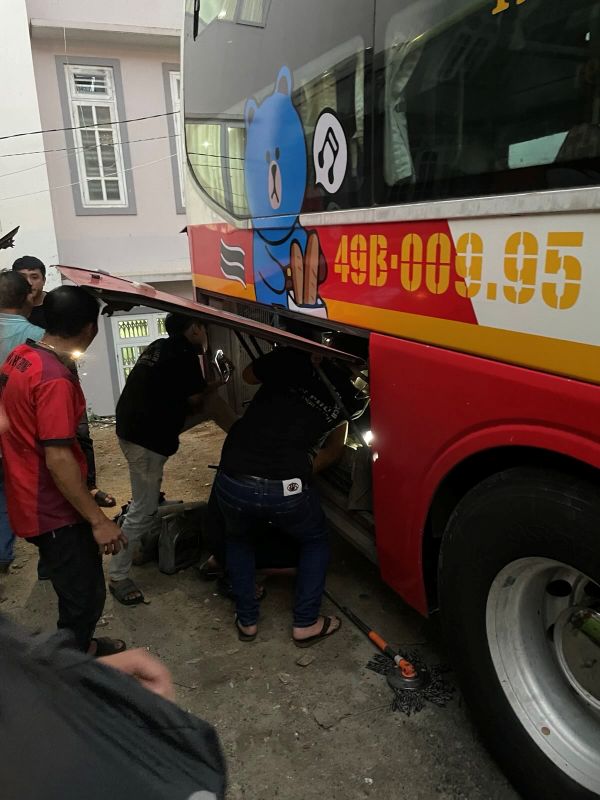 "Die Motorhaube des Busses steht zur Seite geöffnet. Zwei Männer machen sich am Inneren zu schaffen. Am Boden liegt Werkzeug."
