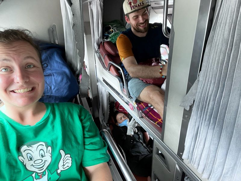 "Sophia und ich sitzen lächelnd in unseren jeweiligen Liegeplätzen im Bus. Alle Sitzplätze haben graue Vorhänge."