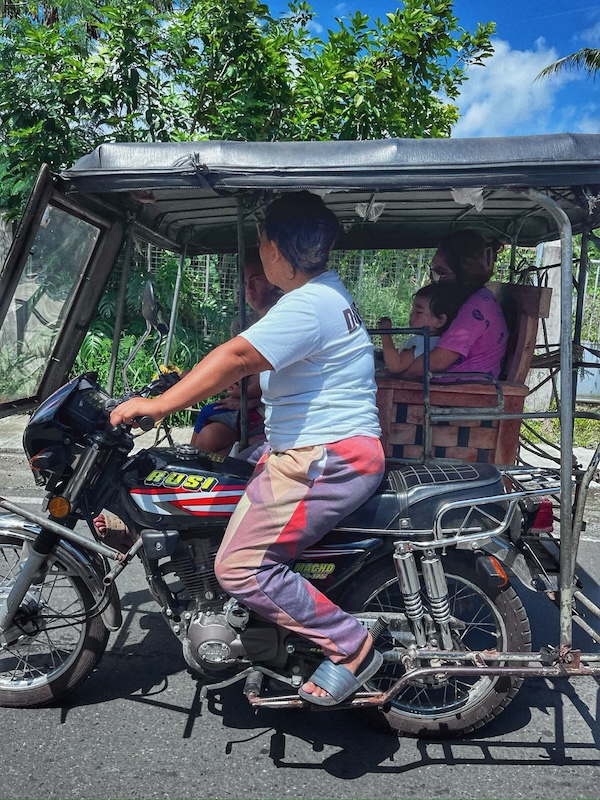 "Eine Frau fährt Motorrad und hat ihre Kinder im Beiwagen, der über einen Holzstuhl verfügt"
