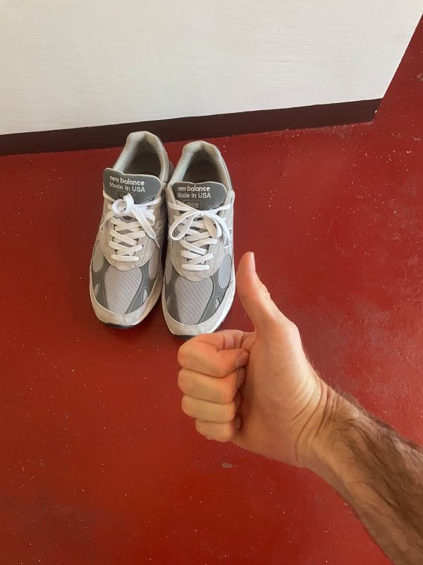 "Auf dem roten Boden stehen meine Schuhe. Das Paar ist wieder vereint. Davor erkennt man meine Hand wie ich den Daumen in die Höhe hebe."