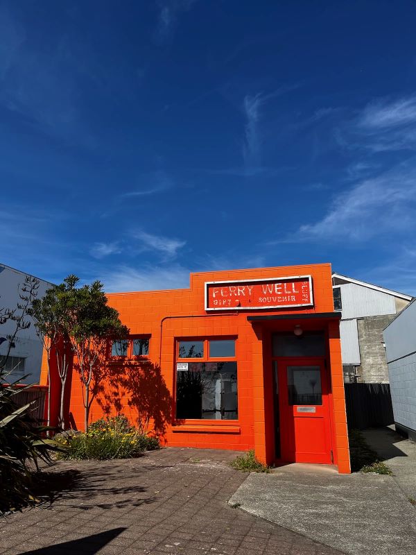 "Ein orangerotes Gebäude mit der Aufschrift "Ferry Well" steht unter einem blauen Himmel."
