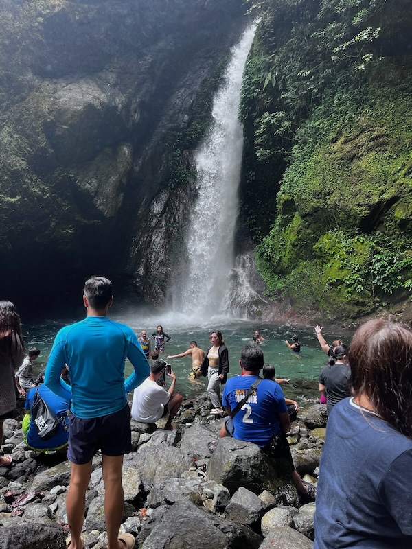 "Am reißerischen Wasserfall sind dutzende Touristen, die Fotos machen, baden oder auf den Steinen sitzen. "