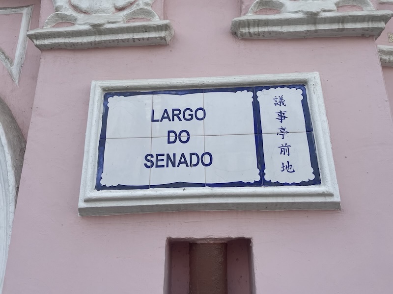 "Ein macanesisches Straßenschild auf Portugiesisch und Chinesisch. Largo do Senado steht darauf."