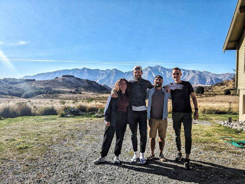 "Sophia, ich, Simon und ich stehen am Schotter vor einer malerischen Hügellandschaft neben der Forest Lodge unter blauem Himmel und Sonnenschein."