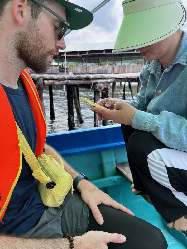 "Ich sitze im Boot und schaue auf mein Handy, das von einer vietnamesischen Frau gehalten wird."