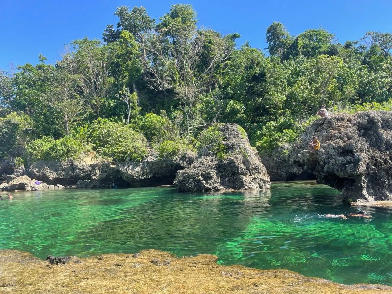 "Ein Felsbecken mit türkis-grünem Wasser, aus dem einige Felsbrocken herausragen."