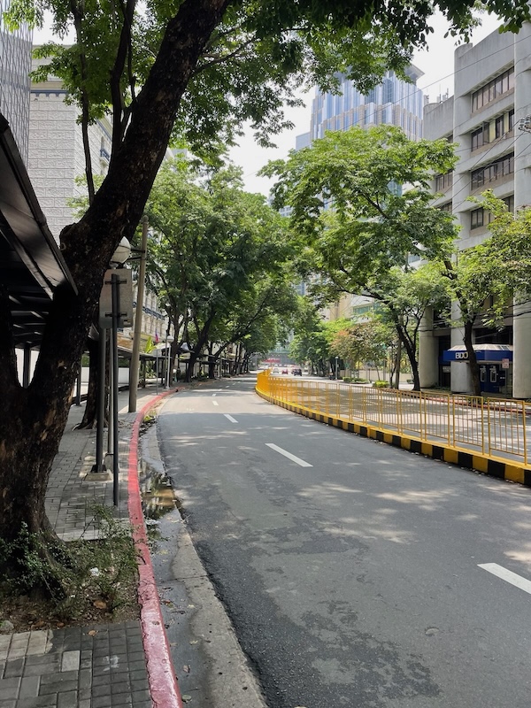 "Die leere Straße in Makati ist sauber und von Bäumen umgeben."