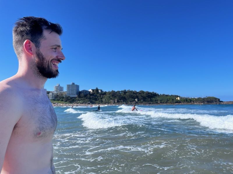 "Ich bin im Profil sichtbar, wie ich im Meer stehe. Ich sehe in Richtung der Wellen. Einige Menschen surfen in den Wellen."