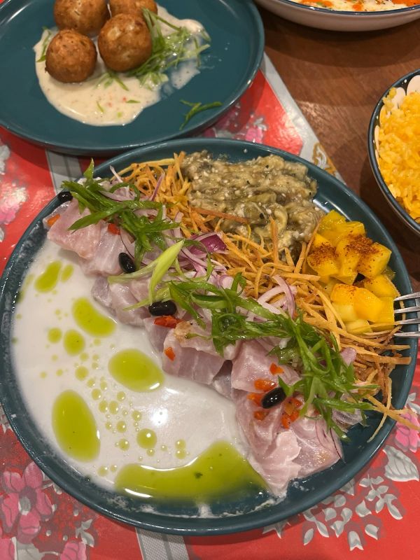 "Ein Teller voller Seviche mit dicker Sauce, Auberginenmuss und Mangostücken"