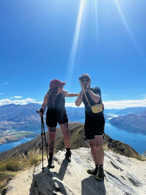 "Sophia und ich posieren vorm malerischen Lake Wanaka und der Berglandschaft. Sophia steht erhöht, hat ihre Wanderstöcke in der Hand und sieht mich an während ihre Hand meine Schulter berührt. Ich halte meine Hände auf meine Wangen und versuche eine klassische koreanische Photopose zu imitieren."